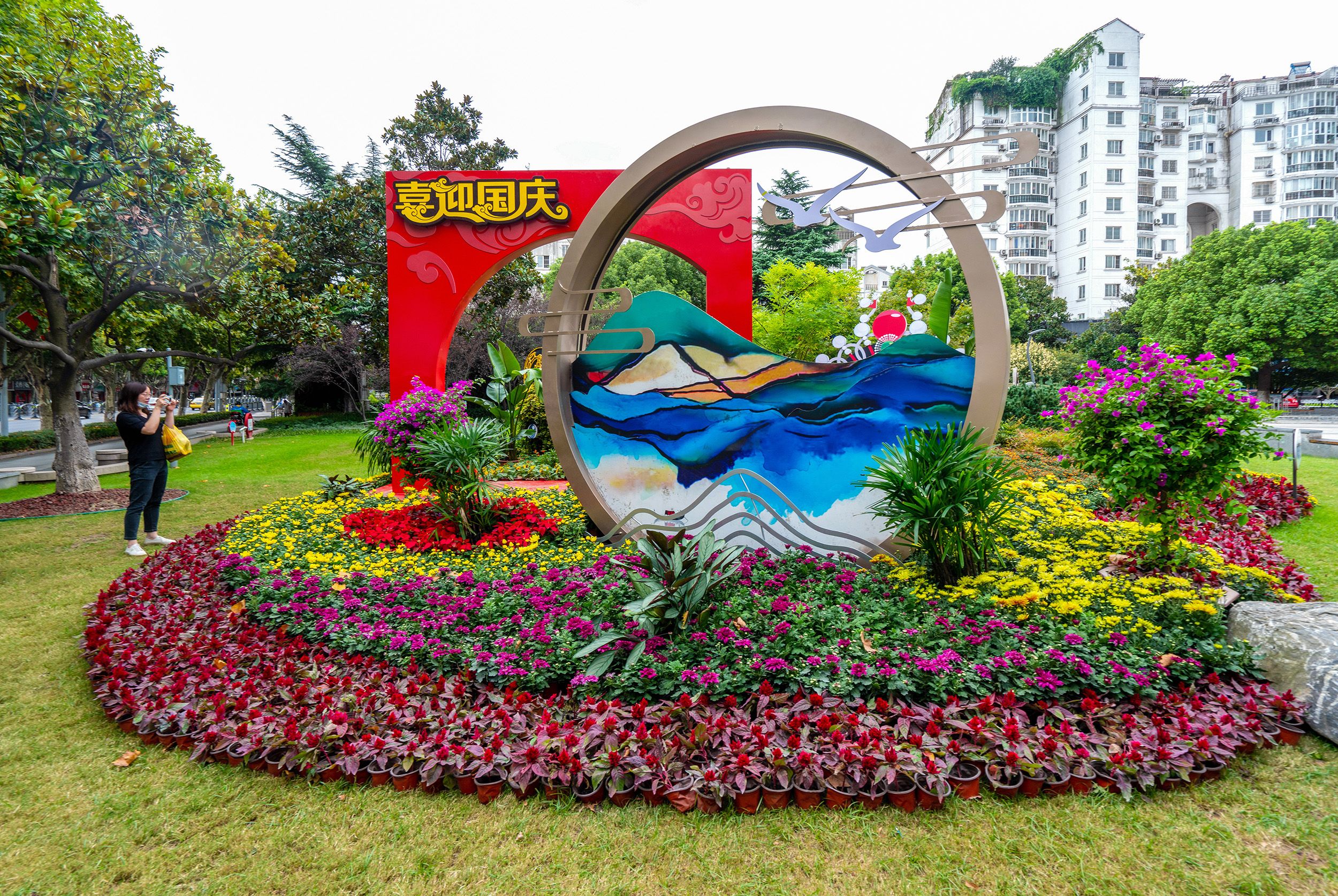 国庆"的灯笼描绘出绚丽多彩的喜庆画面;街角路口的鲜花,绿植景观传递